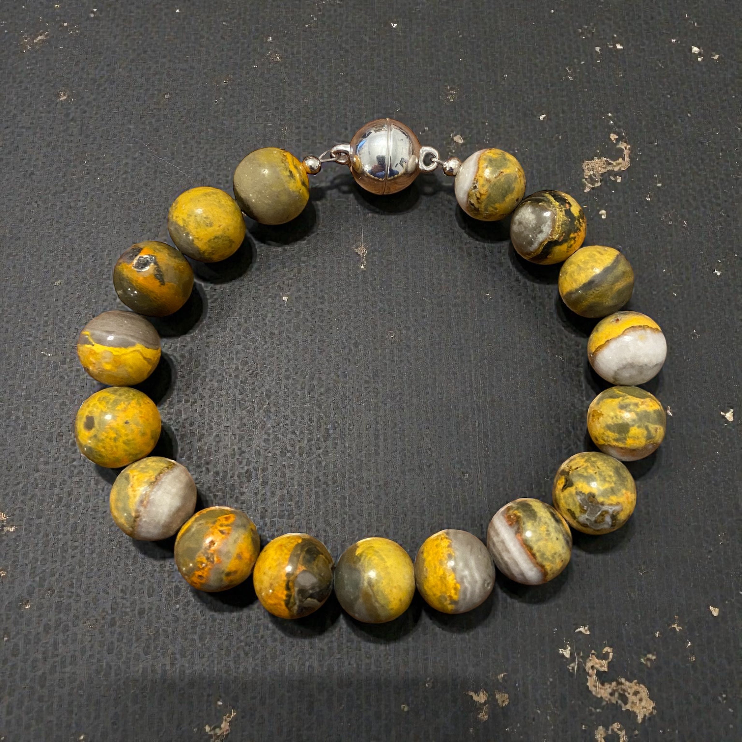 Beaded bracelet with yellow and gray bumble bee jasper stones on a dark textured surface