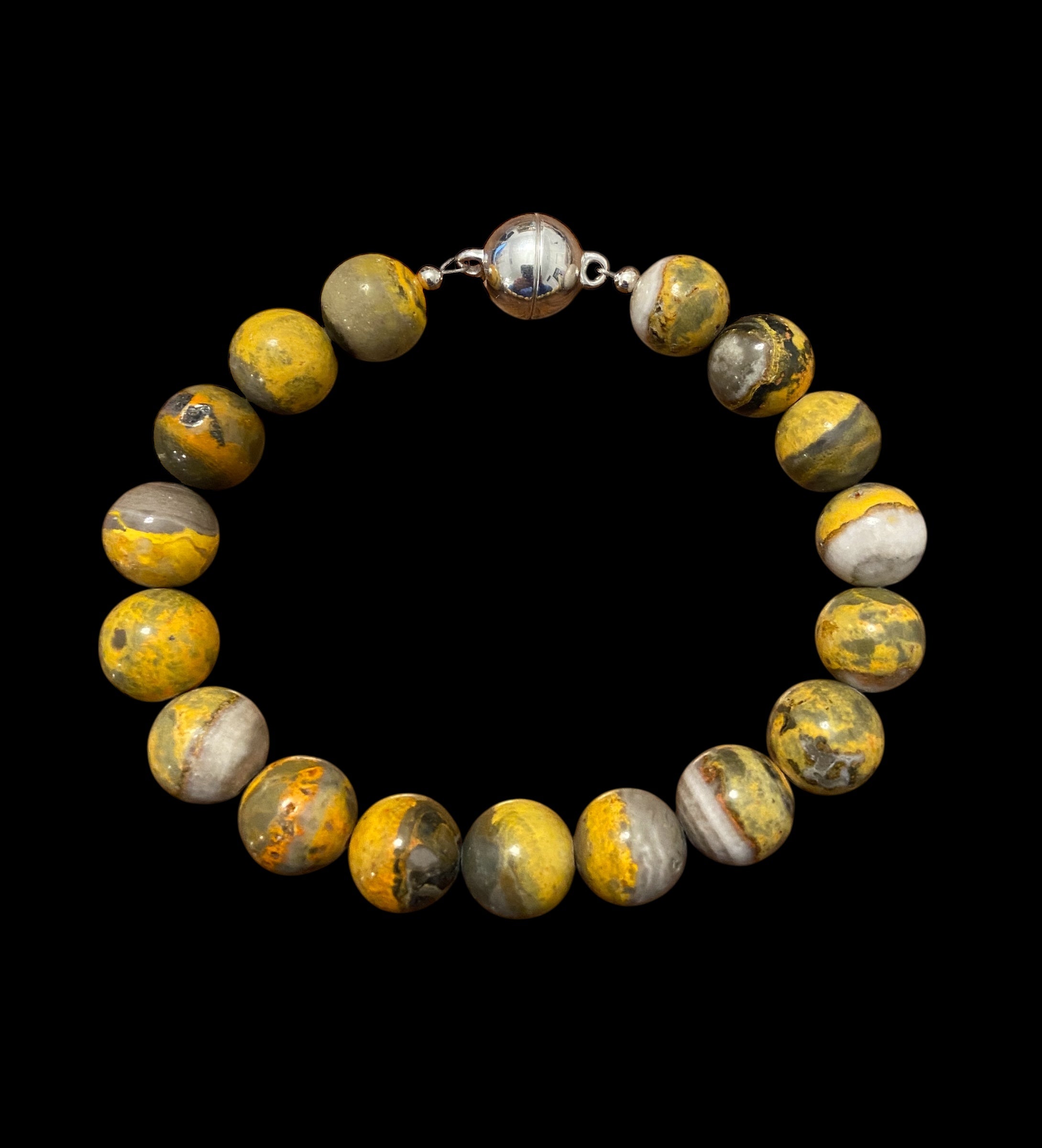 Beaded bracelet with yellow and gray bumble bee jasper gemstones on a black background