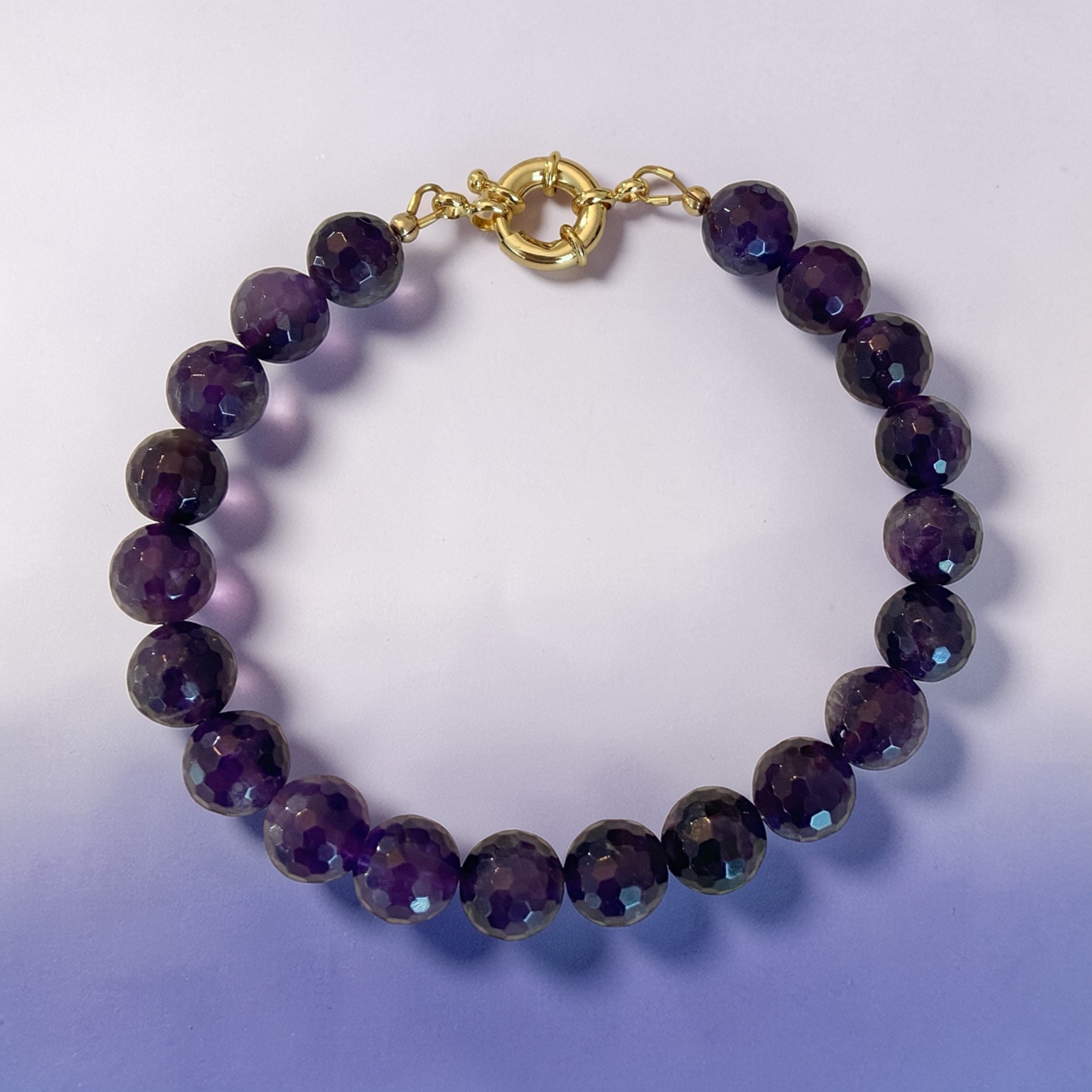 Amethyst beaded bracelet with a 14K gold-filled clasp on a light purple background