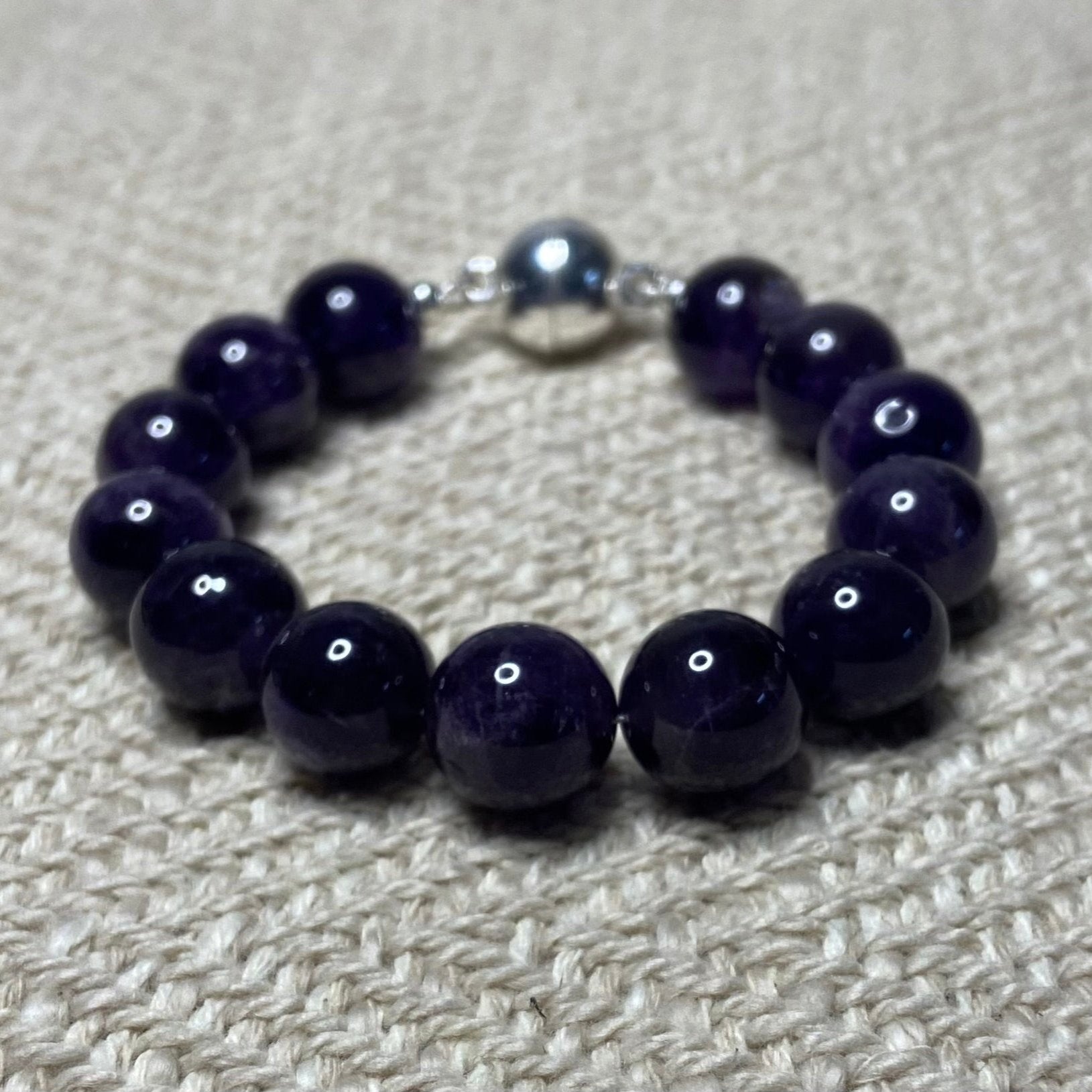 Amethyst beaded bracelet on a textured beige surface