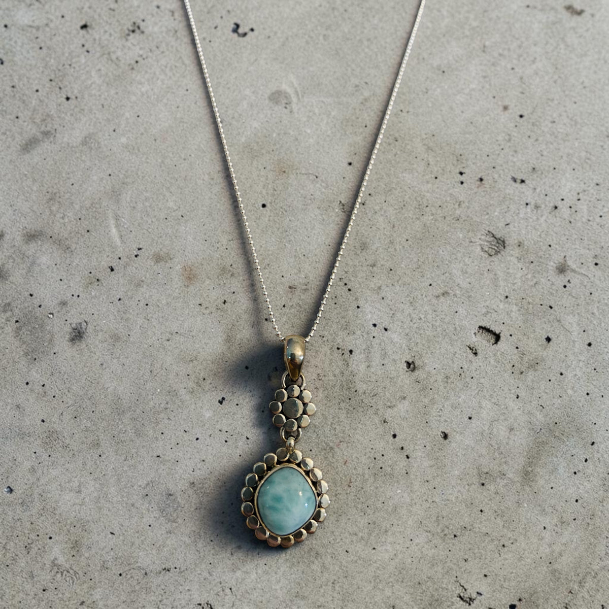 Larimar serenity necklace closeup on gray background.