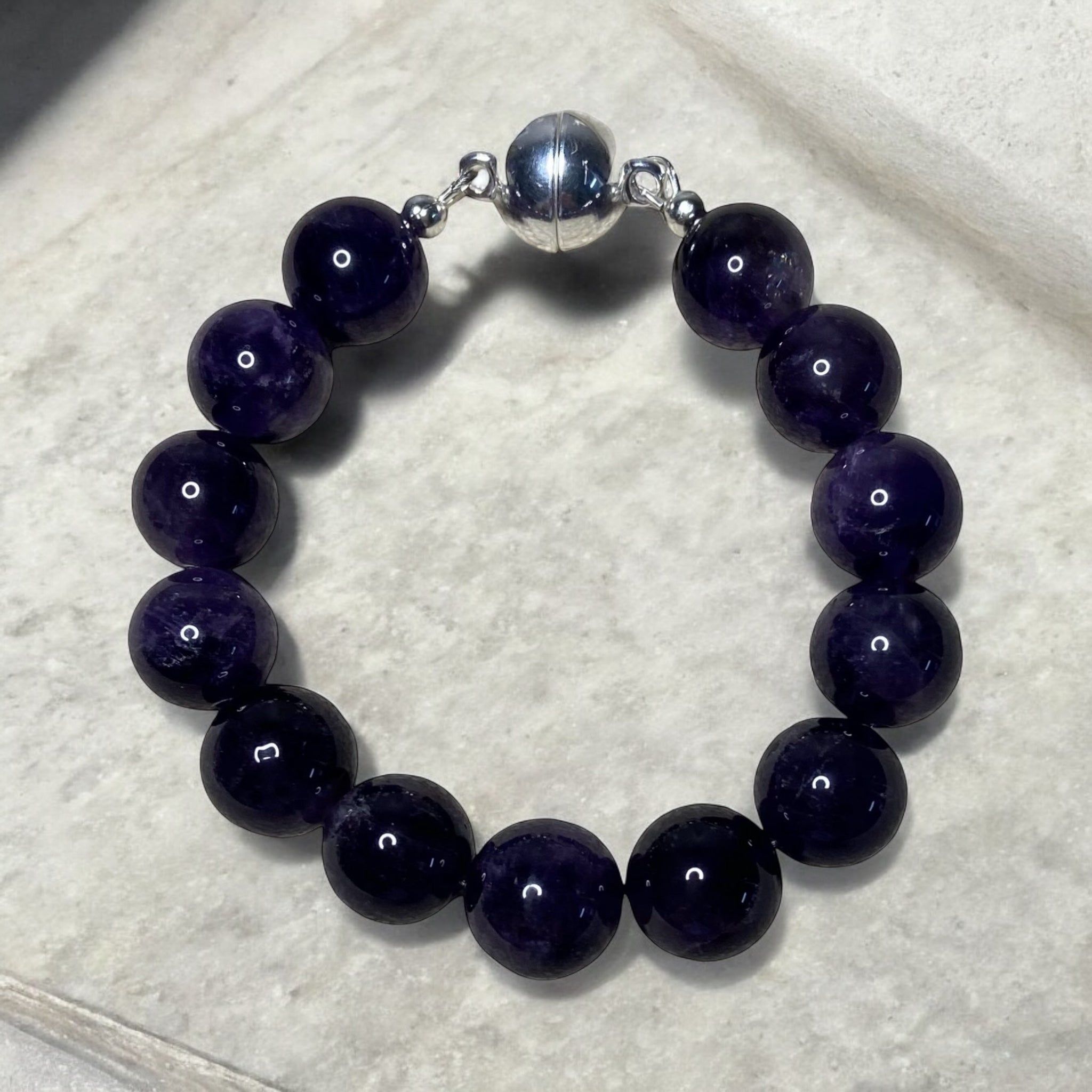 A men's bracelet featuring 12mm amethyst gemstones with a sterling silver magnetic clasp.