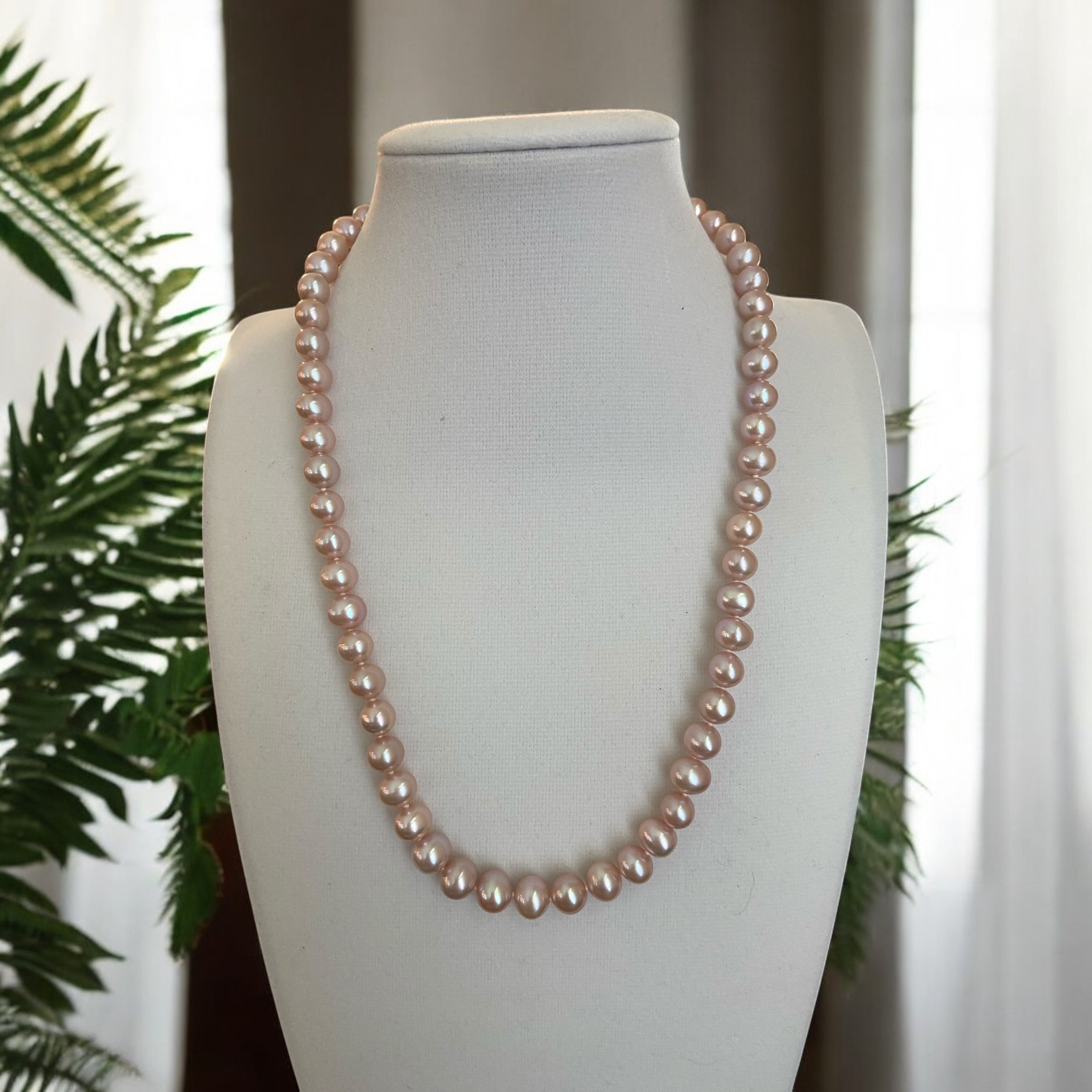 A pink cultured freshwater pearl necklace displayed on a mannequin 